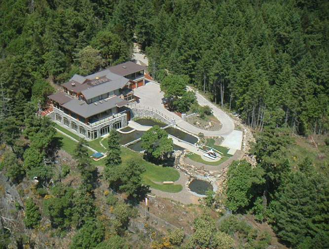 011Aerial-view.jpg - This overhead shot of the estate gives a view of the home and the surroundings. The helicopter has a garage at the other end of the drive, next to the pool within the arched stone windows. Heating throughout the home is geothermal. Although this house is on a steep mountain with spectacular views, many of the Maharishi Vastu homes on Spring Island are nestled in the forest.