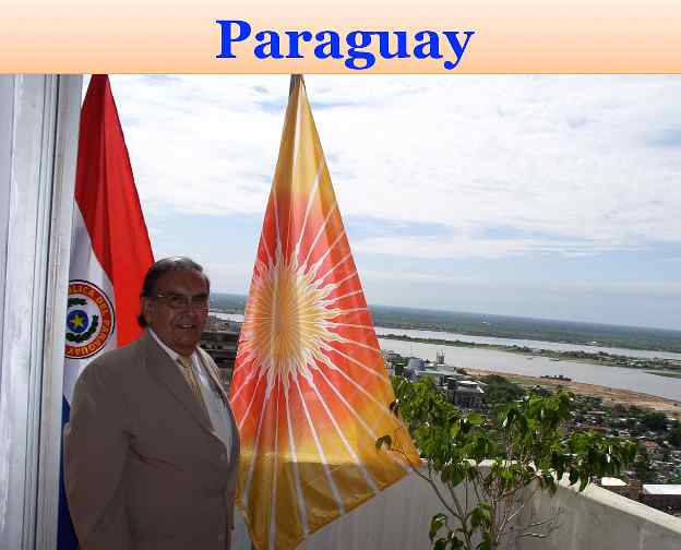 Paraguay.jpg - Paraguay: National Director, Pedro Ojeda, raised the Flag of Invincibility on Victory Day. He pointed out the Governmnet Palace and Paraguay's Congress buildings in the background.