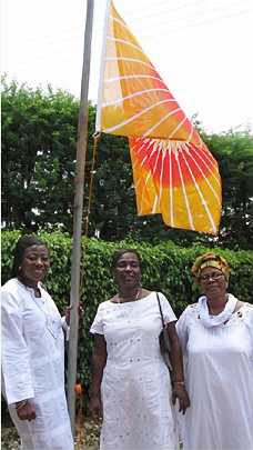 03_Ghana_01.jpg - A new lady Teacher of Transcendental Meditation for Ghana, the first in the country, who is also the GMDO National Director, raises the flag of Invincibility. She recently taught Transcendental Meditation to all the ladies in a factory in Accra, as well as all the ladies and girls in an after-school programme.