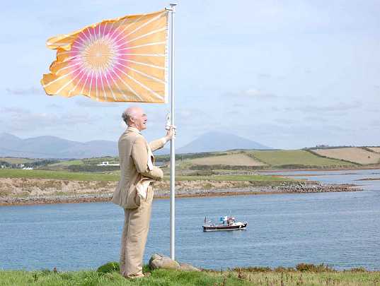 12-Joe-with-flag.jpg - After listening to the Rastragit, the anthem of the Global Country of World Peace, National Director Joe Hayden raises the Flag of Invincibility on the Maharishi Island of World Peace.