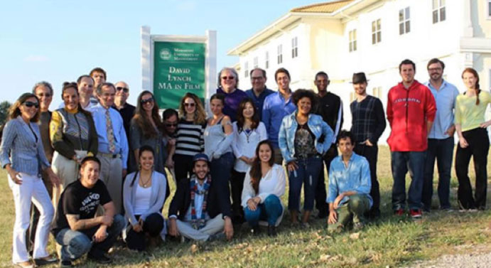 lynch4.jpg - Students and faculty in the David Lynch MA in Film gather outside the departmental sign as they prepare for the first day of class.