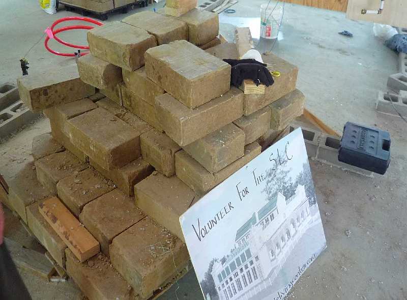 Slide27.jpg - A pile of some of the 26,000 compact earth blocks the students have made with earth taken from the parking lot at the Argiro Center. The blocks are perfect for thermal mass, and replace concrete masonry units.