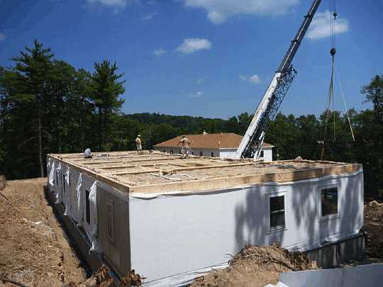 Slide0005.jpg - A crane hoists modules into place for the 10-suite residential building. It takes 10 days to build the module at a factory, one day to install it at the site, and a month to complete finishing touches.