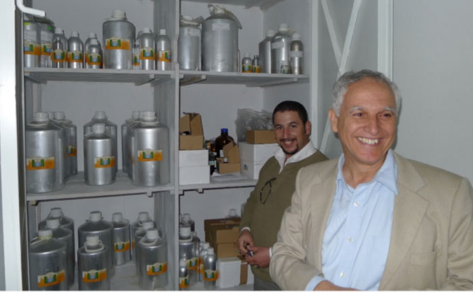 111s.jpg - Mr Atmane Kouider and his son Amine show a supply cabinet of essential oils rendered from an almost unimaginable amount of flower petals and other raw materials.