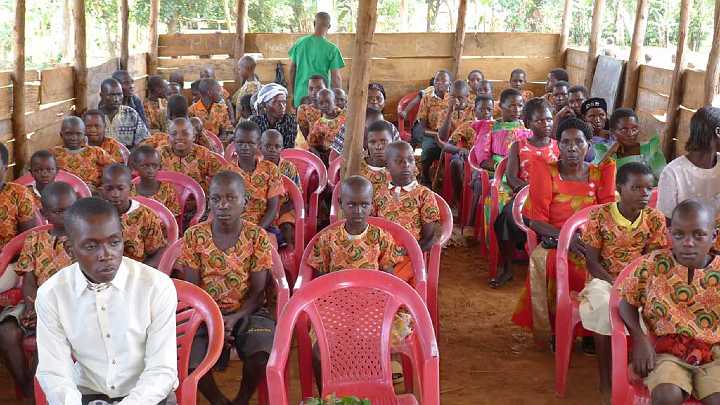 Uganda-GGn-(32).jpg - Students with some of their caregivers meet with Dr Morris and Dr de Freitas. They are seated in their simple, one-room school house.