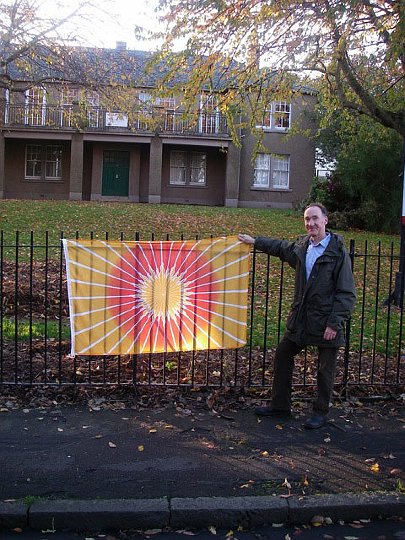 52-Scotland.jpg - David Ray, National Director for Scotland, holds the Flag of Invincibility before a new centre for Transcendental Meditation in Edinburgh. It is a large building meeting Vastu requirements with 10 rooms for centre activities.